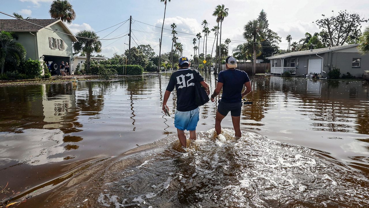 Thomas Chaves, left, and Vinny Almeida walk through floodwaters from Hurricane Helene in an attempt to reach Chaves's mother's house in the Shore Acres neighborhood Friday, Sept. 27, 2024, in St. Petersburg, Fla. (AP Photo/Mike Carlson)