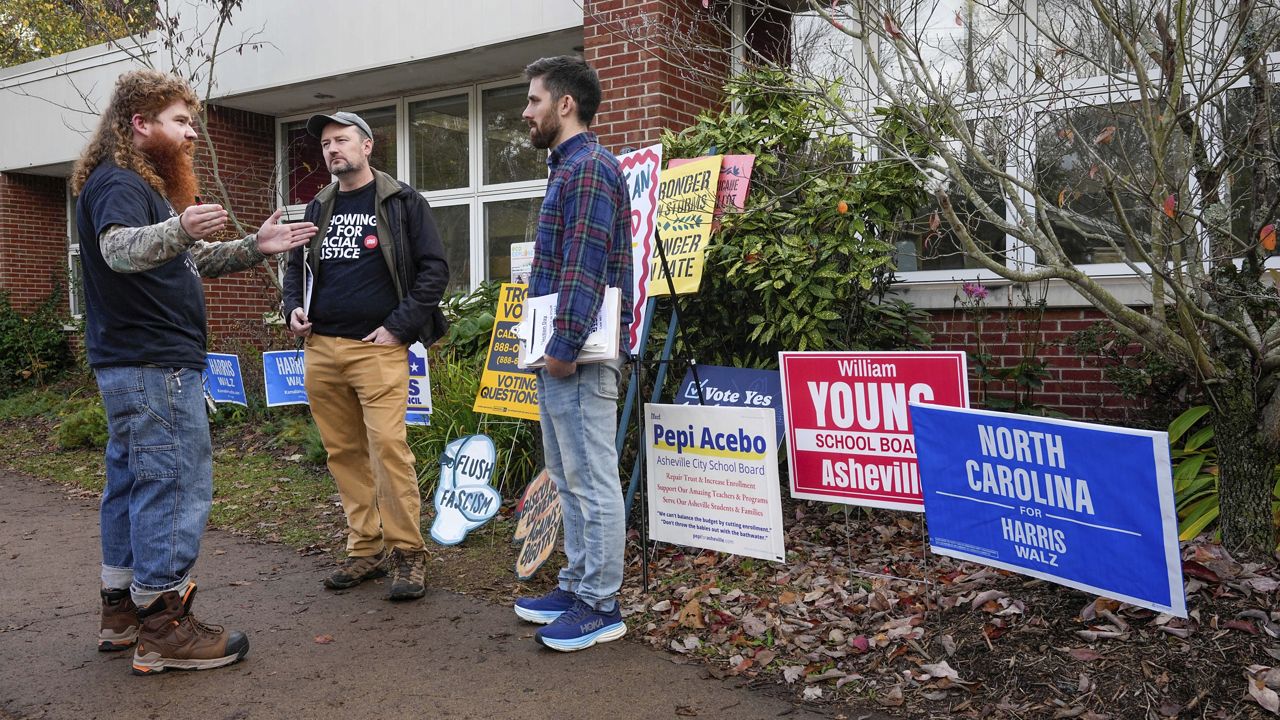 University of North Carolina at Asheville student, Elijah Walker-Haigh, left, speaks with advocates for Vice President Kamala Harris, Greg Horwitch, middle, and David Dean outside the West Asheville Public Library on Election Day, Tuesday, Nov. 5, 2024 in Asheville, N.C. (AP Photo/Kathy Kmonicek)