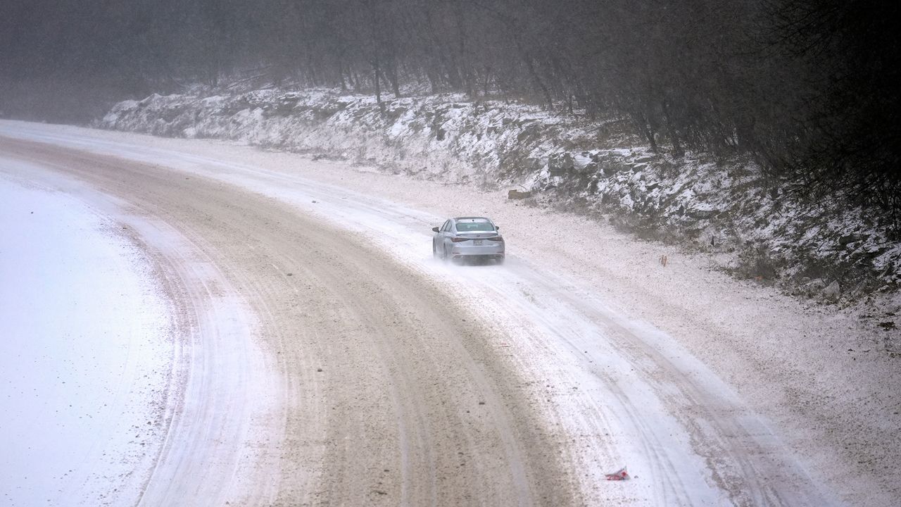 A car slowly navigates a snow-covered interstate Sunday, Jan. 5, 2025, in St. Louis. (AP Photo/Jeff Roberson)