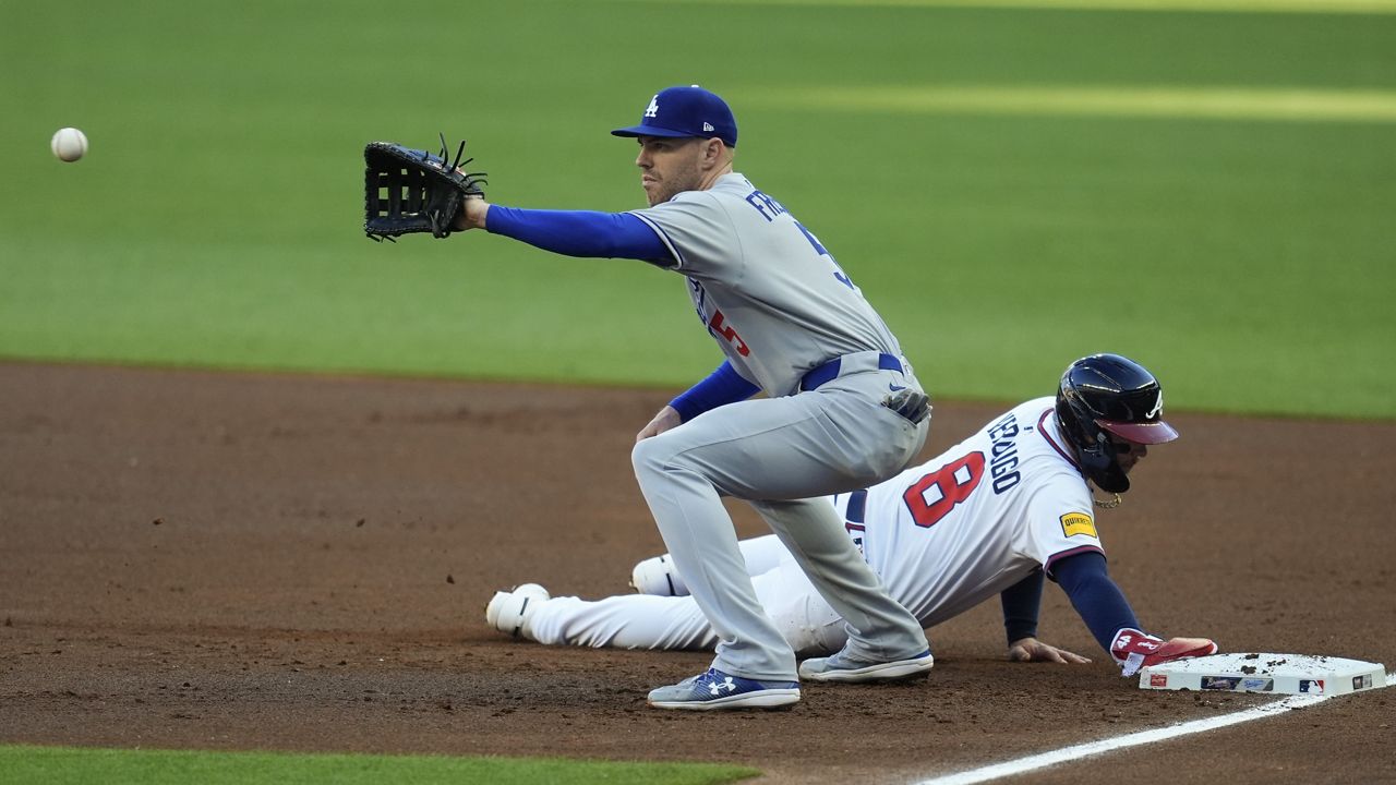 Atlanta Braves' Alex Verdugo (8) makes it back to first base against Los Angeles Dodgers first baseman Freddie Freeman (5) in the first inning of a baseball game, Sunday, May 4, 2025, in Atlanta. (AP Photo/Mike Stewart)