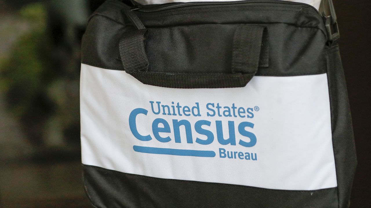 FILE - A census taker carries a briefcase as she knocks on the door of a residence in Winter Park, Fla., Aug. 11, 2020. (AP Photo/John Raoux, File)