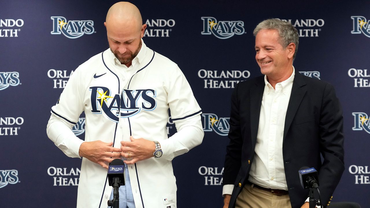 Tampa Bay Rays owner Stuart Sternberg, right, looks on as former Rays third baseman Evan Longoria puts on a jersey after signing a one-day contract to retire as a member of the team during a news conference before a baseball game between the Tampa Bay Rays and the Miami Marlins Saturday, June 7, 2025, in Tampa, Fla. (AP Photo/Chris O'Meara)