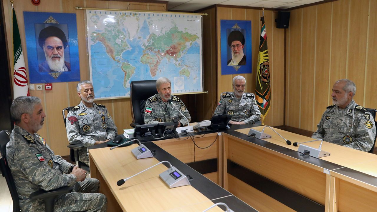In this photo released on Monday, 23, 2025, by Iranian army press service, Iran's army commander-in-chief Gen. Amir Hatami, center, accompanied by high ranked army commanders, speaks in a video call with top commanders of the army, in Zolfaghar central headquarters, Iran, as portraits of the late revolutionary founder Ayatollah Khomeini, left, and Supreme Leader Ayatollah Ali Khamenei hang on the wall. (Iranian Army Press Service via AP)