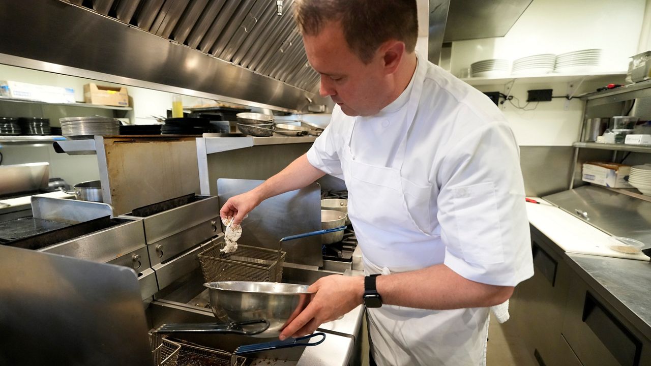 Executive chef Benjamin Hasty drops a breaded green crab into a fryer at Signal restaurant Tuesday, June 16, 2026, in Kennebunk, Maine. (AP Photo/Robert F. Bukaty)