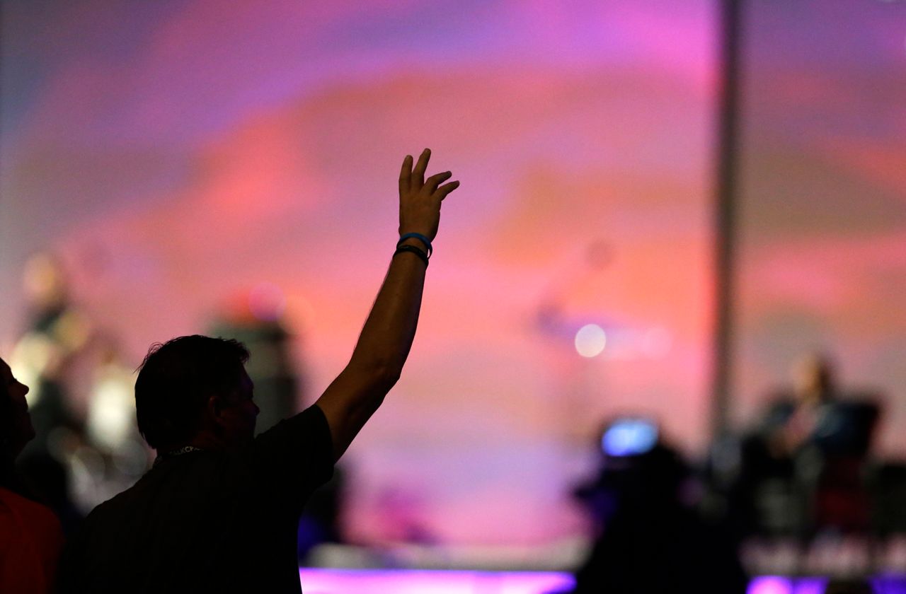 A man raises his arm during worship. 