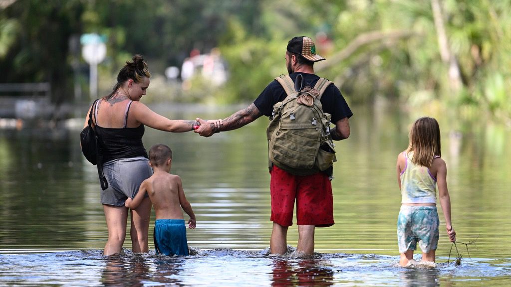 Dustin Holmes, second from right, holds hands with his girlfriend, Hailey Morgan, while returning to their flooded home with her children Aria Skye Hall, 7, right, and Kyle Ross, 4, in the aftermath of Hurricane Helene, Friday, Sept. 27, 2024, in Crystal River, Fla. (AP Photo/Phelan M. Ebenhack)