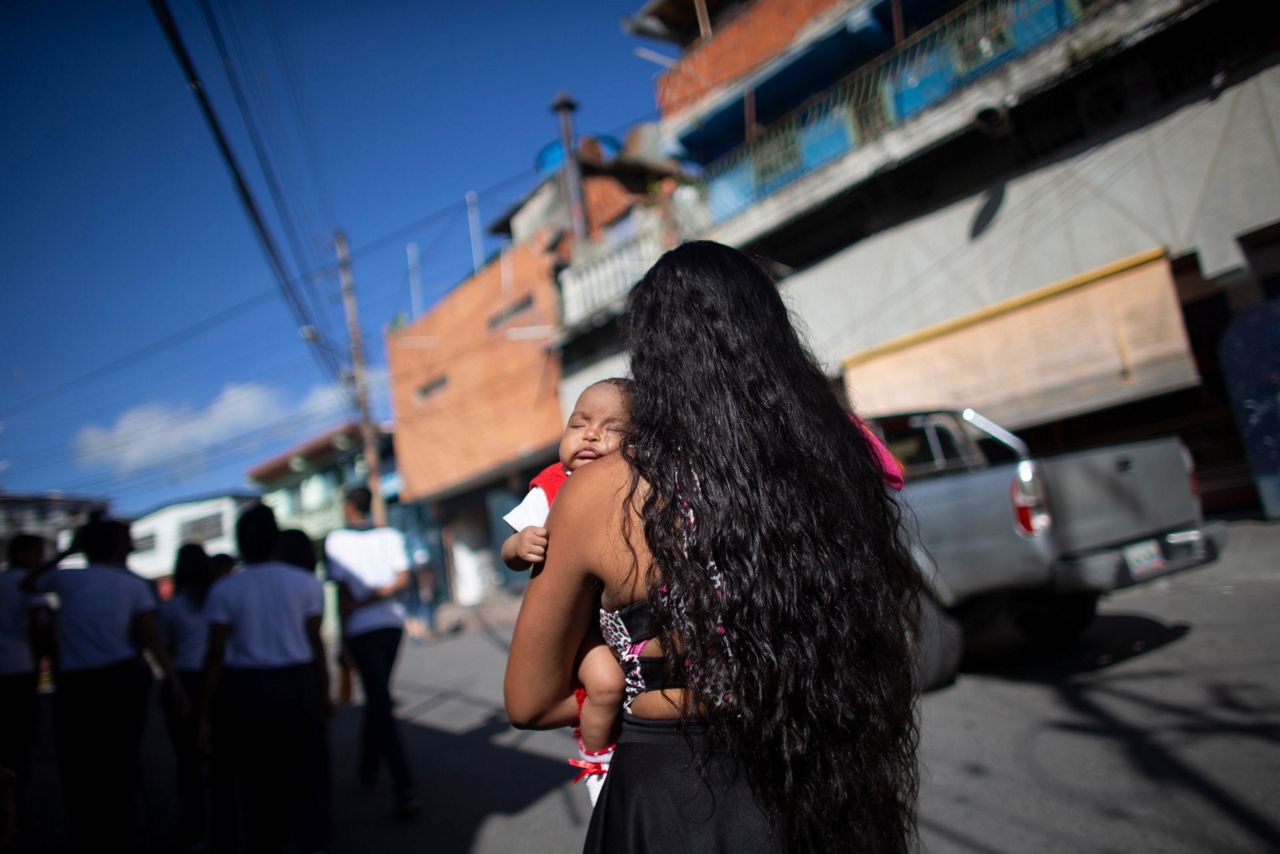 In this photo taken July 25, 2019, 15-year-old Nicol Ramirez carries her ba...