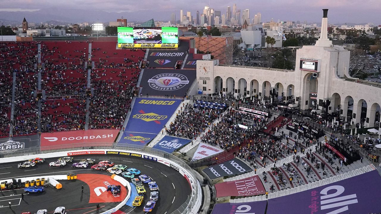 Cars race around the track as downtown Los Angeles is seen in the background during the Busch Light Clash NASCAR exhibition auto race at Los Angeles Memorial Coliseum Sunday, Feb. 5, 2023, in Los Angeles. (AP Photo/Mark J. Terrill