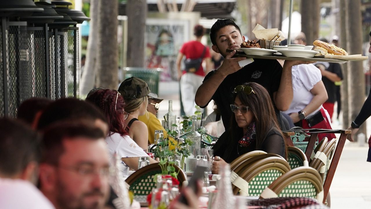 A waiter delivers food to patrons at a restaurant, Jan. 21, 2022, in Miami Beach, Fla. (AP Photo/Marta Lavandier)