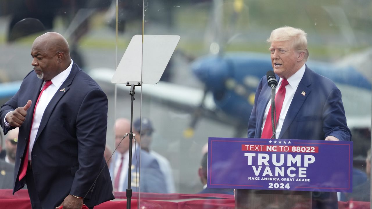 North Carolina Lt. Gov. Mark Robinson, left, walks past former President Donald Trump, right, after being introduced at a Trump campaign event in Asheboro, N.C., Wednesday, Aug. 21, 2024. Robinson is the Republican candidate for N.C. governor. (AP Photo/Chuck Burton)