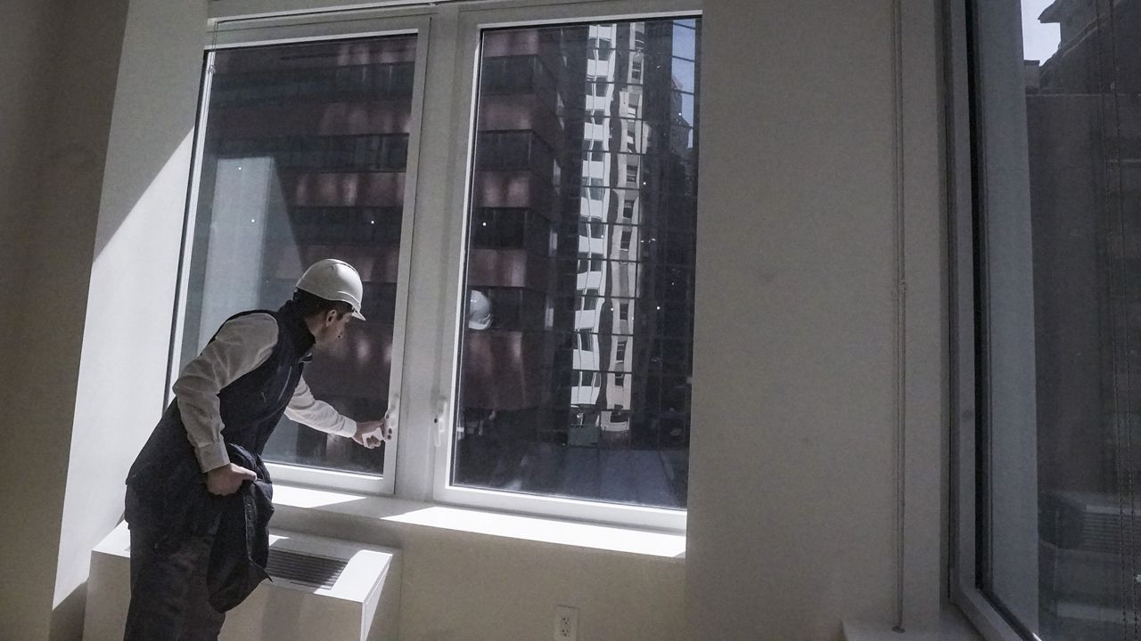 Joey Chilelli, managing director of real estate firm Vanbarton Group, demonstrates a window designed to protect birds from crashes, during a tour of a model apartment at a high rise undergoing conversion from commercial to residential apartments, Tuesday, April 11, 2023, in New York. (AP Photo/Bebeto Matthews)