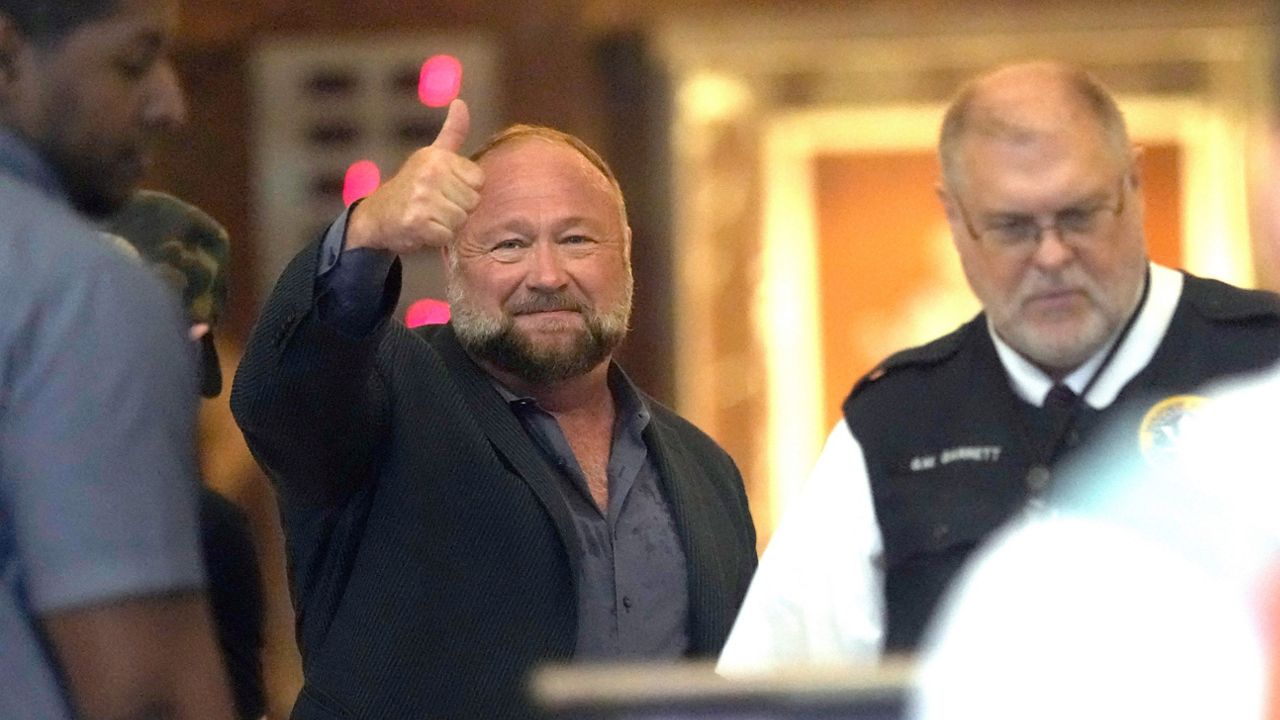 Right-wing conspiracy theorist Alex Jones gives a thumbs-up as he goes through security at the federal courthouse after arriving for a hearing in front of a bankruptcy judge Friday, June 14, 2024, in Houston. (AP Photo/David J. Phillip)