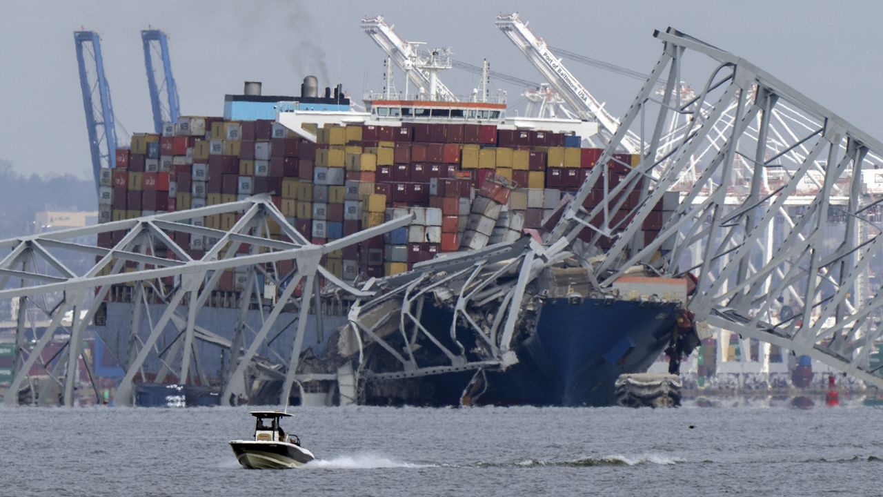 A boat moves past a container ship as it rests against wreckage of the Francis Scott Key Bridge on Tuesday, March 26, 2024, as seen from Pasadena, Md. (AP Photo/Mark Schiefelbein, File)