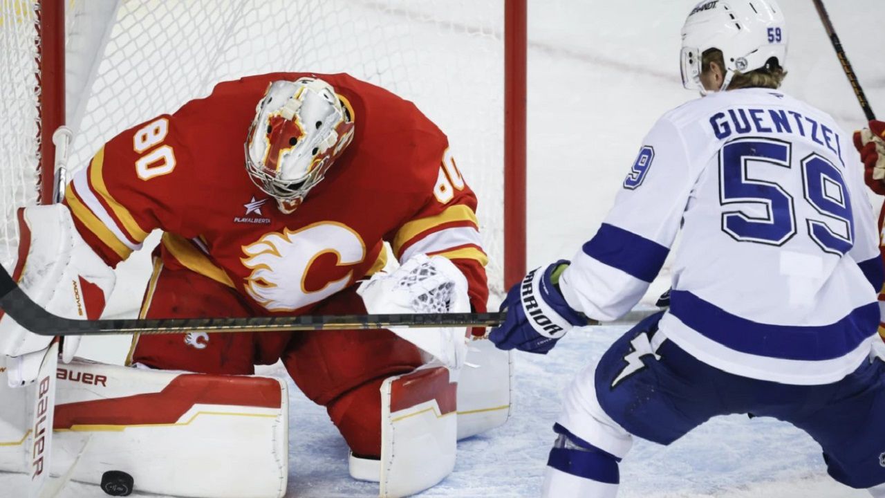 Tampa Bay Lightning's Jake Guentzel, right, has his shot blocked by Calgary Flames goalie Dan Vladar, left, during second-period NHL hockey game action in Calgary, Alberta, Thursday, Dec. 12, 2024. (Jeff McIntosh/The Canadian Press via AP)