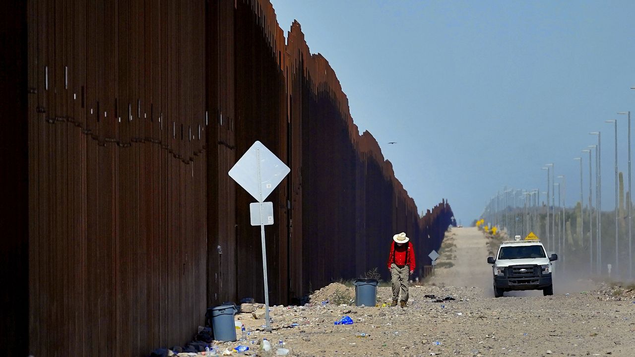 Retired schoolteacher Tom Wingo, of Samaritans Without Borders, walks on the Roosevelt Easement picking up trash along the border fence as a U.S. Customs and Border Patrol agent patrols the area, Aug. 29, 2023, in Organ Pipe Cactus National Monument near Lukeville, Ariz. (AP Photo/Matt York, File)