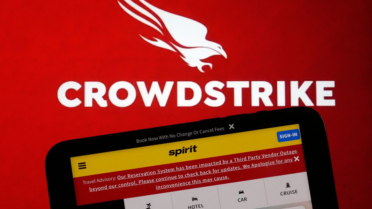 The logo for CrowdStrike and a Spirit Airlines webpage are shown on a computer screen and mobile phone screen, in New York, Friday, July 19, 2024. A global technology outage grounded flights, knocked banks offline and media outlets off air after a faulty software update disrupted companies and services around the world and highlighted their dependence on just a handful of providers. (AP Photo/Richard Drew)