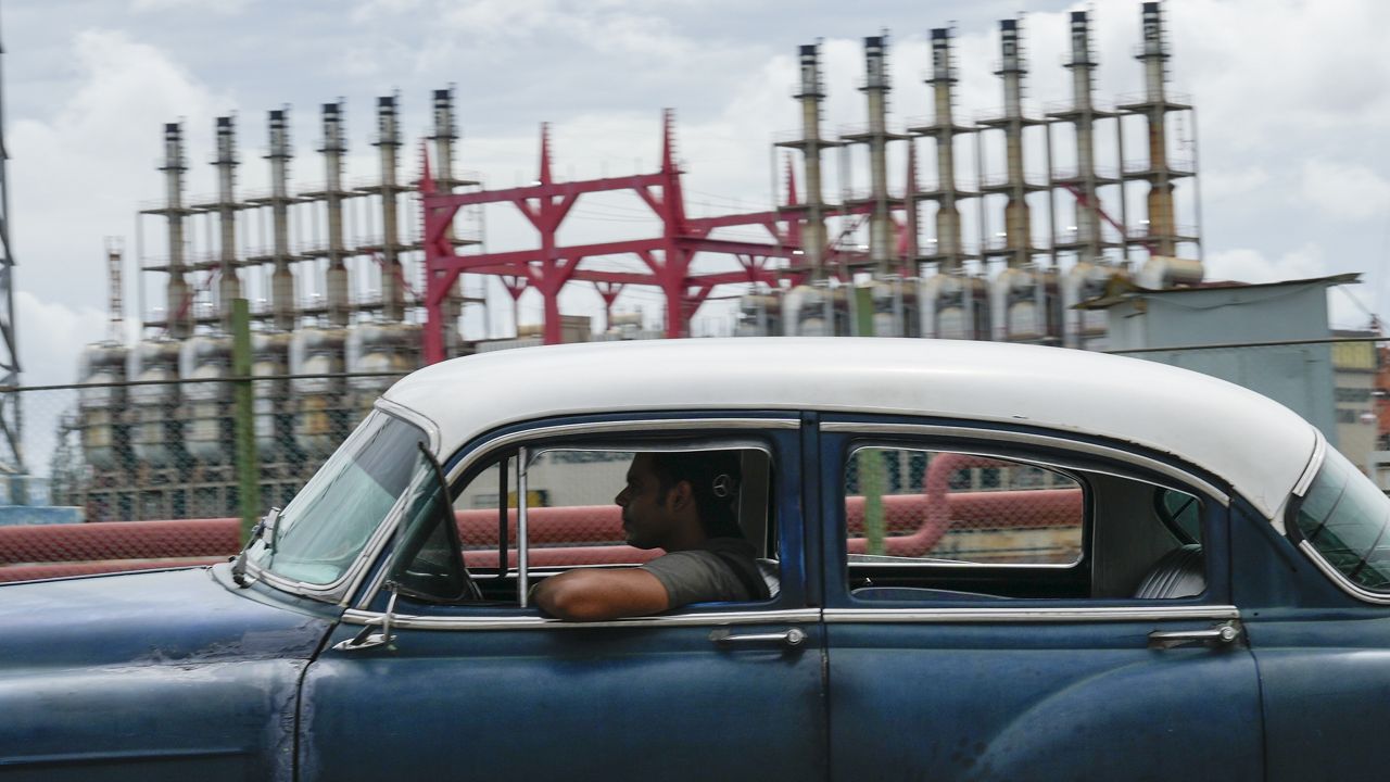 A person drives a classic American car past a floating generator that has not been producing electricity for days in Havana, Cuba, Friday, Oct. 18, 2024. (AP Photo/Ramon Espinosa)