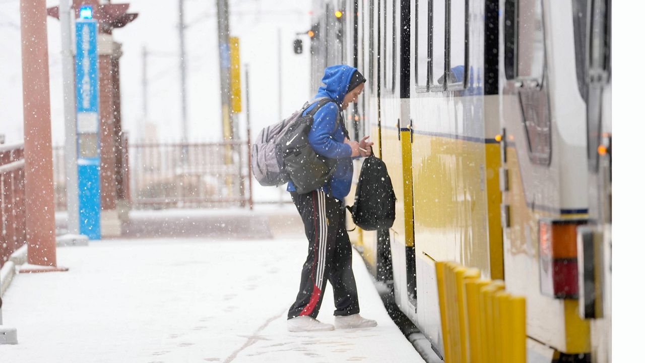 Snow falls as a person boards a DART train Thursday, Jan. 9, 2025, in Dallas. (AP Photo/LM Otero)