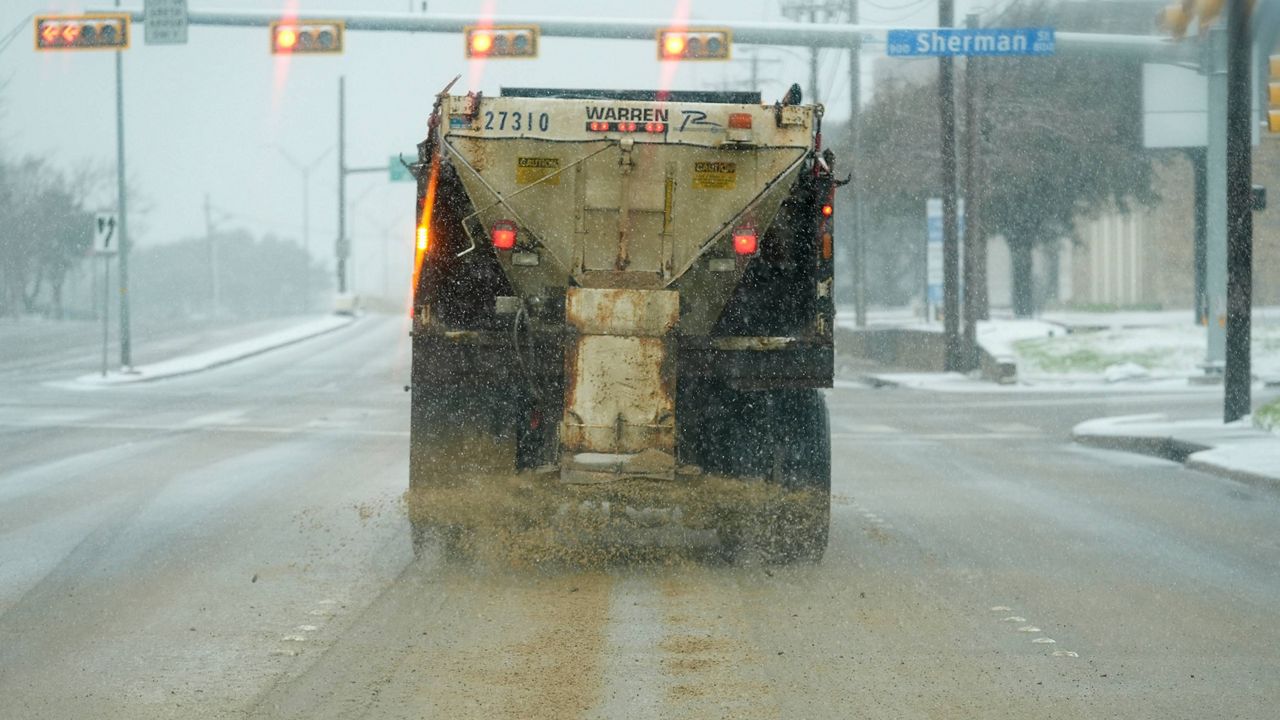 A truck treats a road for better driving conditions as snow falls Thursday, Jan. 9, 2025, in Dallas. (AP Photo/LM Otero)