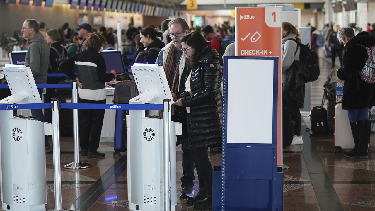 Travellers queue up at the Jet Blue Airlines self-check-in kiosks in Denver International Airport Tuesday, Dec. 24, 2024, in Denver. (AP Photo/David Zalubowski)