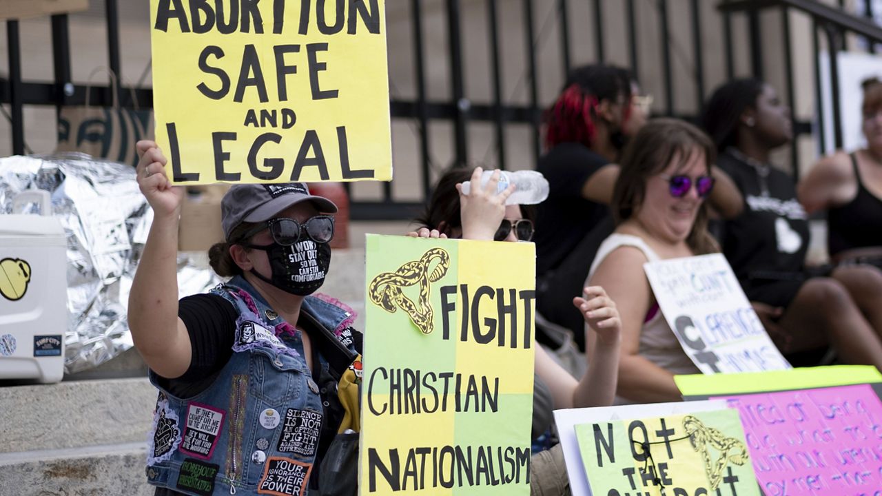 A small group sits on the steps of the Georgia state Capitol protesting the overturning of Roe v. Wade on June 26, 2022. (AP Photo/Ben Gray)