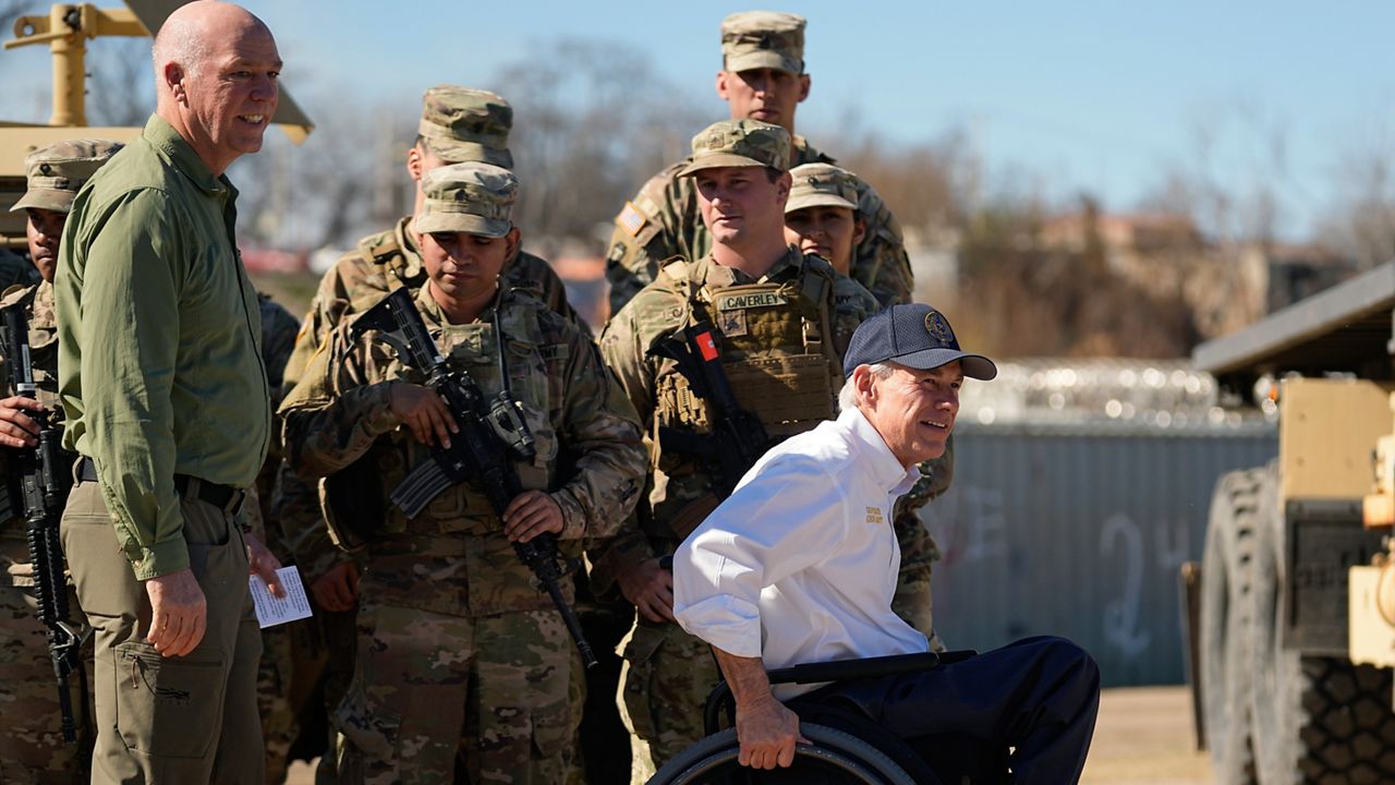Texas Gov. Greg Abbott, right, and Montana Gov. Greg Gianforte, left, walk past members of the National Guard as they arrive with fellow governors for a news conference along the Rio Grande to discuss Operation Lone Star and border concerns, Sunday, Feb. 4, 2024, in Eagle Pass, Texas. (AP Photo/Eric Gay)