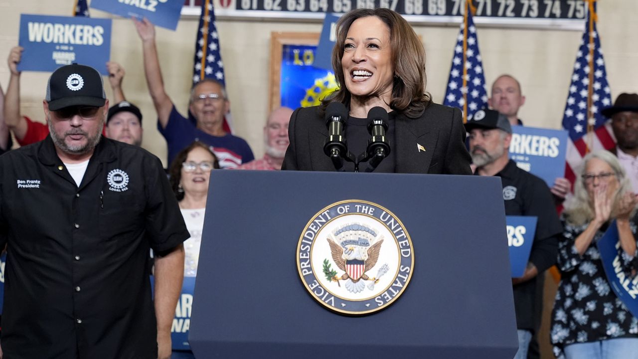 Democratic presidential nominee Vice President Kamala Harris speaks as Benjamin Frantz, left, president of UAW Local 652, looks on at UAW Local 652 during a campaign event in Lansing, Mich., Friday, Oct. 18, 2024. (AP Photo/Jacquelyn Martin)