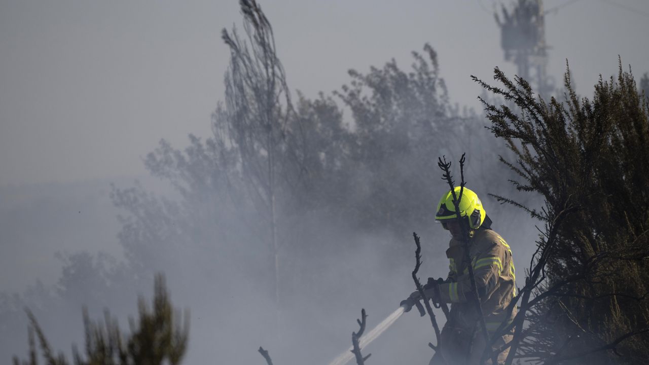 A firefighter works to extinguish a fire after a rocket, fired from Lebanon, hit an area next to a road near Kiryat Shmona, northern Israel, Saturday, Oct. 5, 2024. (AP Photo/Leo Correa)