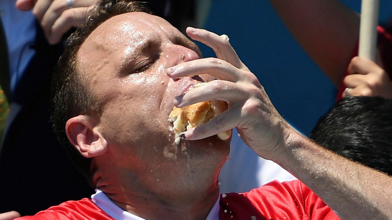 Joey Chestnut stuffs his mouth with hot dogs during the men's competition of Nathan's Famous July Fourth hot dog eating contest, July 4, 2019, in New York's Coney Island. (AP Photo/Sarah Stier, File)