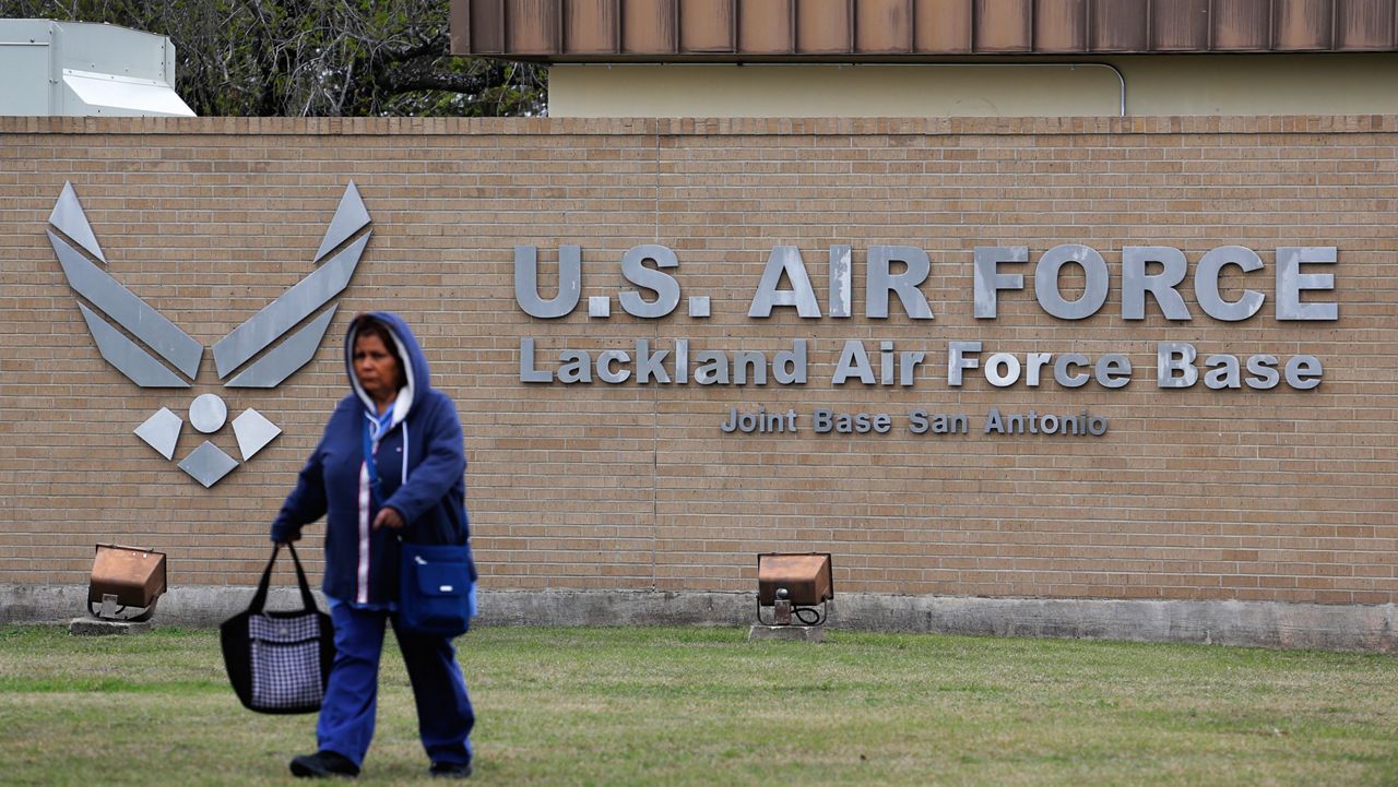 A pedestrian passes the main gate at Lackland Air Force Base in San Antonio, Wednesday, Feb. 5, 2020. (AP Photo/Eric Gay, File)