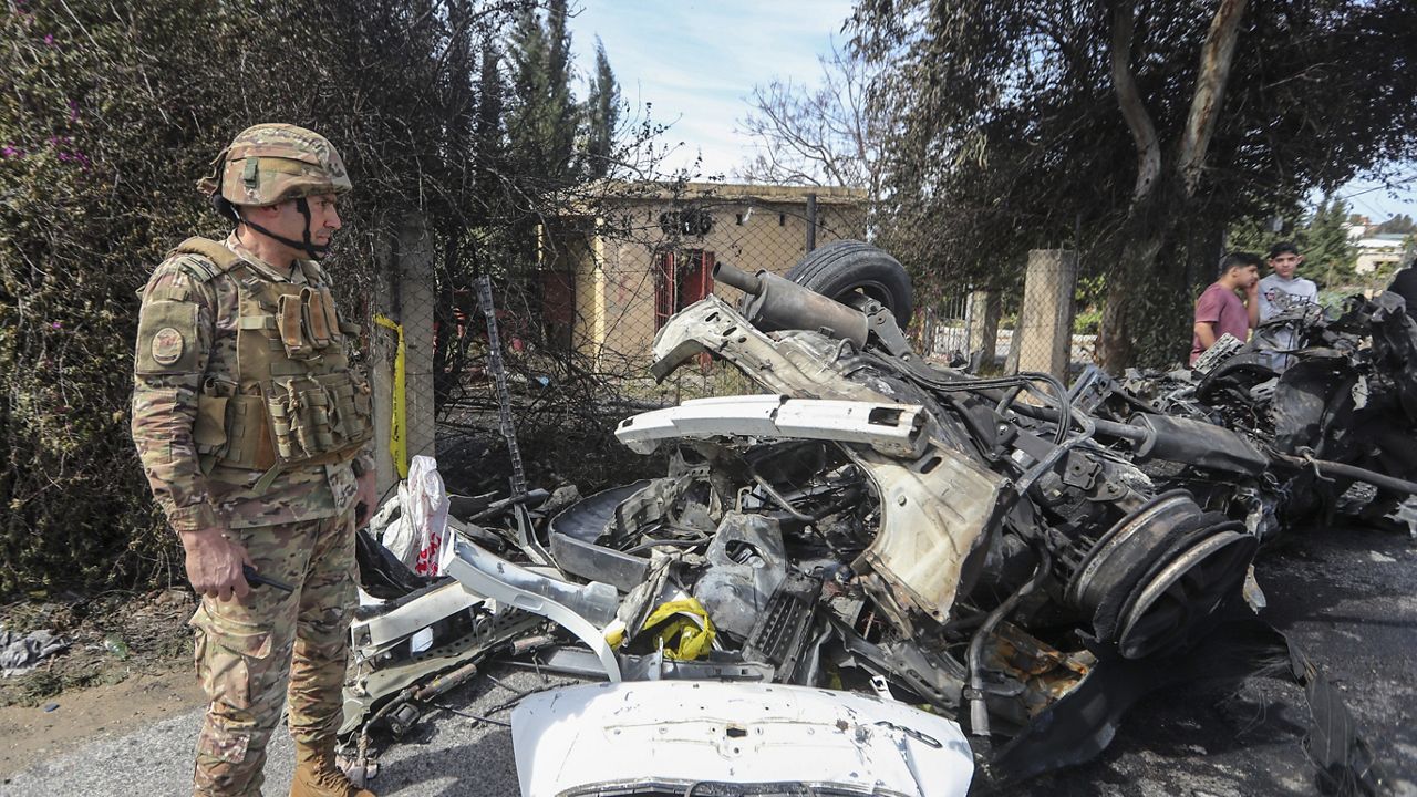 A Lebanese army officer stands next to a destroyed car in the southern outskirts of Tyre, Lebanon, Wednesday, March 13, 2024. (AP Photo/Mohammad Zaatari)