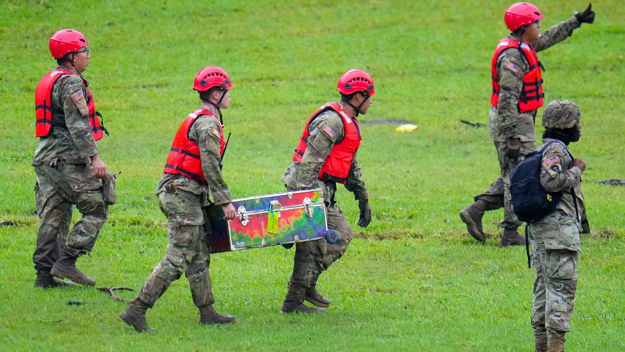 Military personnel carry a camp trunk salvaged down river from Camp Mystic along the Guadalupe River after a flash flood swept through the area Sunday, July 6, 2025, in Hunt, Texas. (AP Photo/Julio Cortez)