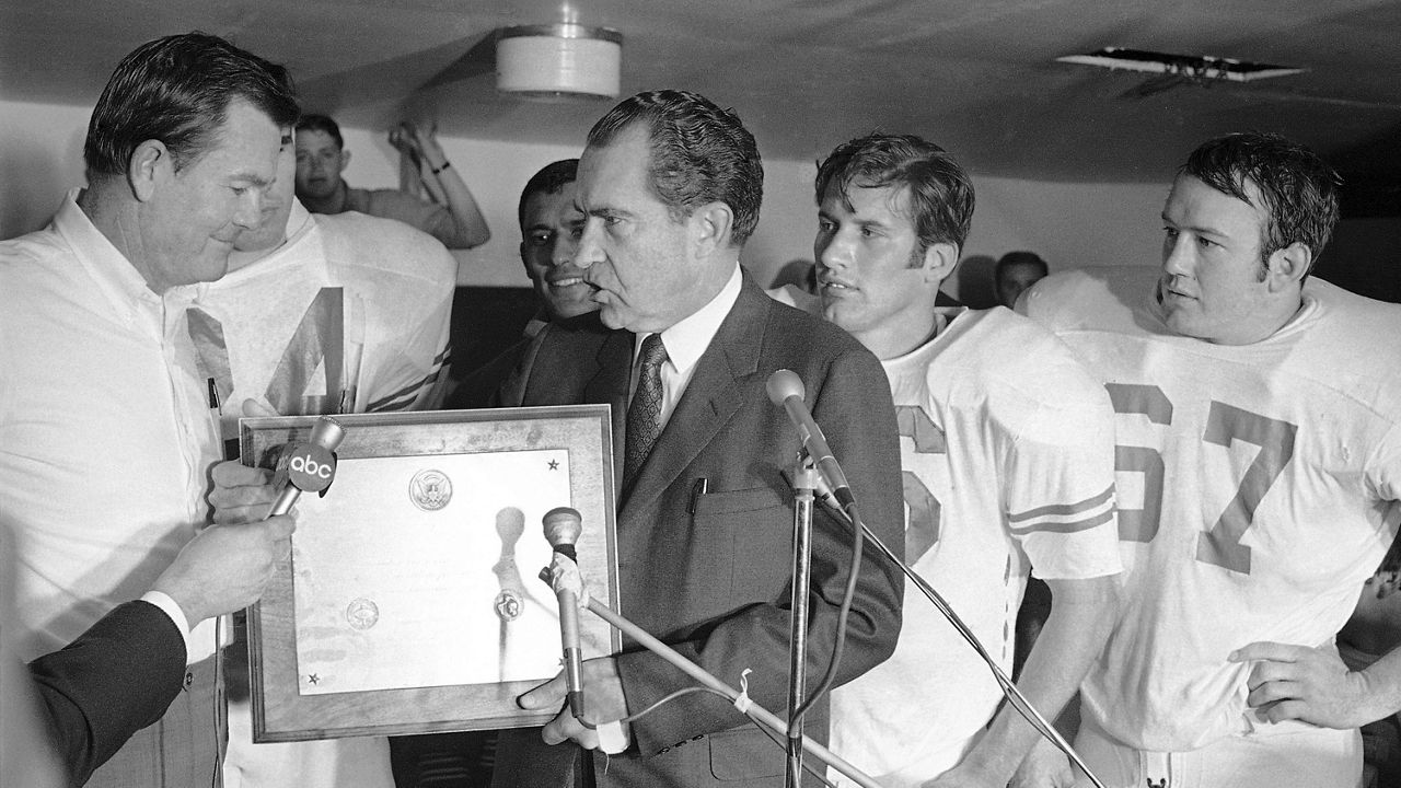 President Richard Nixon presents a plaque to Texas football coach Darrell Royal, naming the Longhorns the No. 1 college football team in college football as linebacker Glen Halsell (67) and quarterback James Street (16) watch, Dec. 6, 1969. (AP Photo)