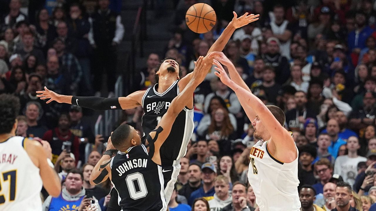 Denver Nuggets center Nikola Jokic, right, passes the ball as San Antonio Spurs forward Keldon Johnson, front left, and center Victor Wembanyama defend in the second half of an NBA basketball game Friday, Jan. 3, 2025, in Denver. (AP Photo/David Zalubowski)