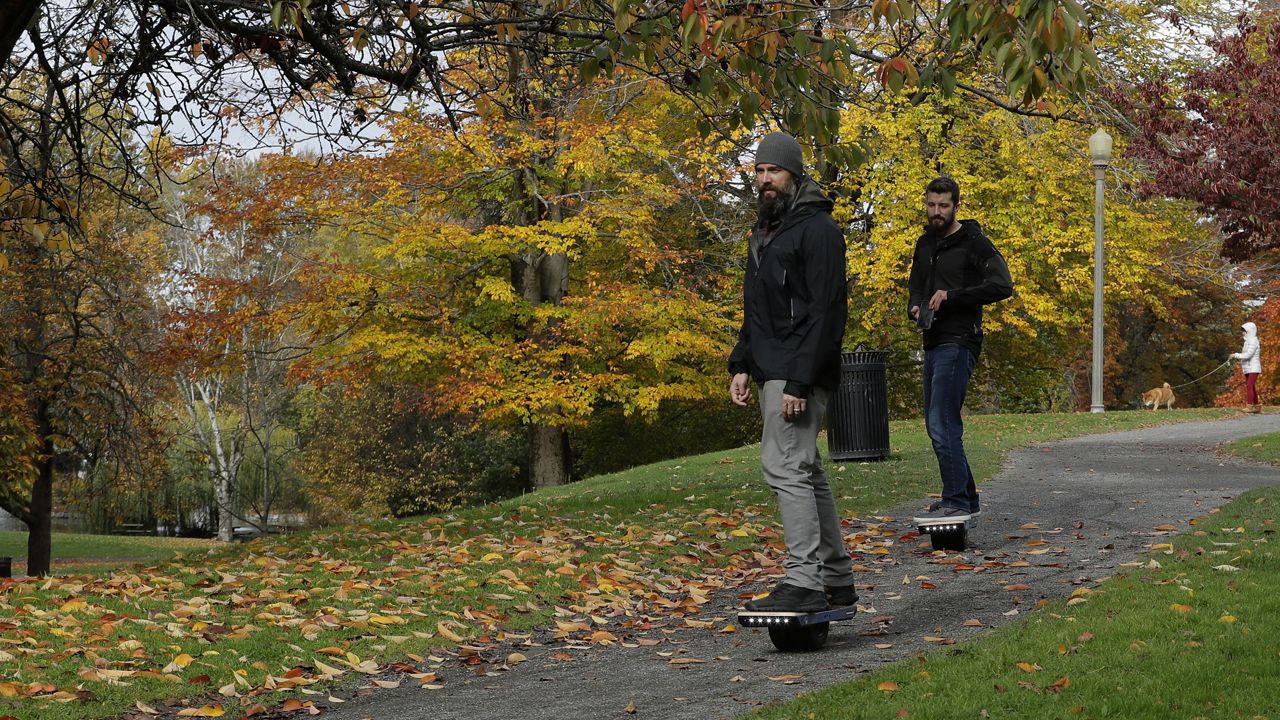Two people ride Onewheels through Wright Park in Tacoma, Wash., on Oct. 26, 2018. (AP Photo/Ted S. Warren)