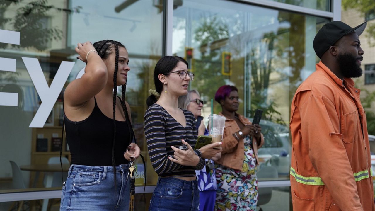 Bystanders watch as Pittsburgh police and other law enforcement personal respond to gunfire in the Garfield neighborhood of Pittsburgh on Wednesday, Aug. 23, 2023. (Benjamin B. Braun/Pittsburgh Post-Gazette via AP)