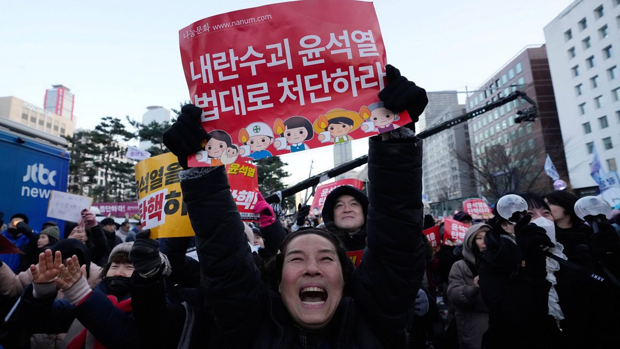 Participants celebrate after hearing the news that South Korea's parliament voted to impeach President Yoon Suk Yeol outside the National Assembly in Seoul, South Korea, Saturday, Dec. 14, 2024. The signs read "Punish the rebellion leader Yoon Suk Yeol." (AP Photo/Ahn Young-joon)