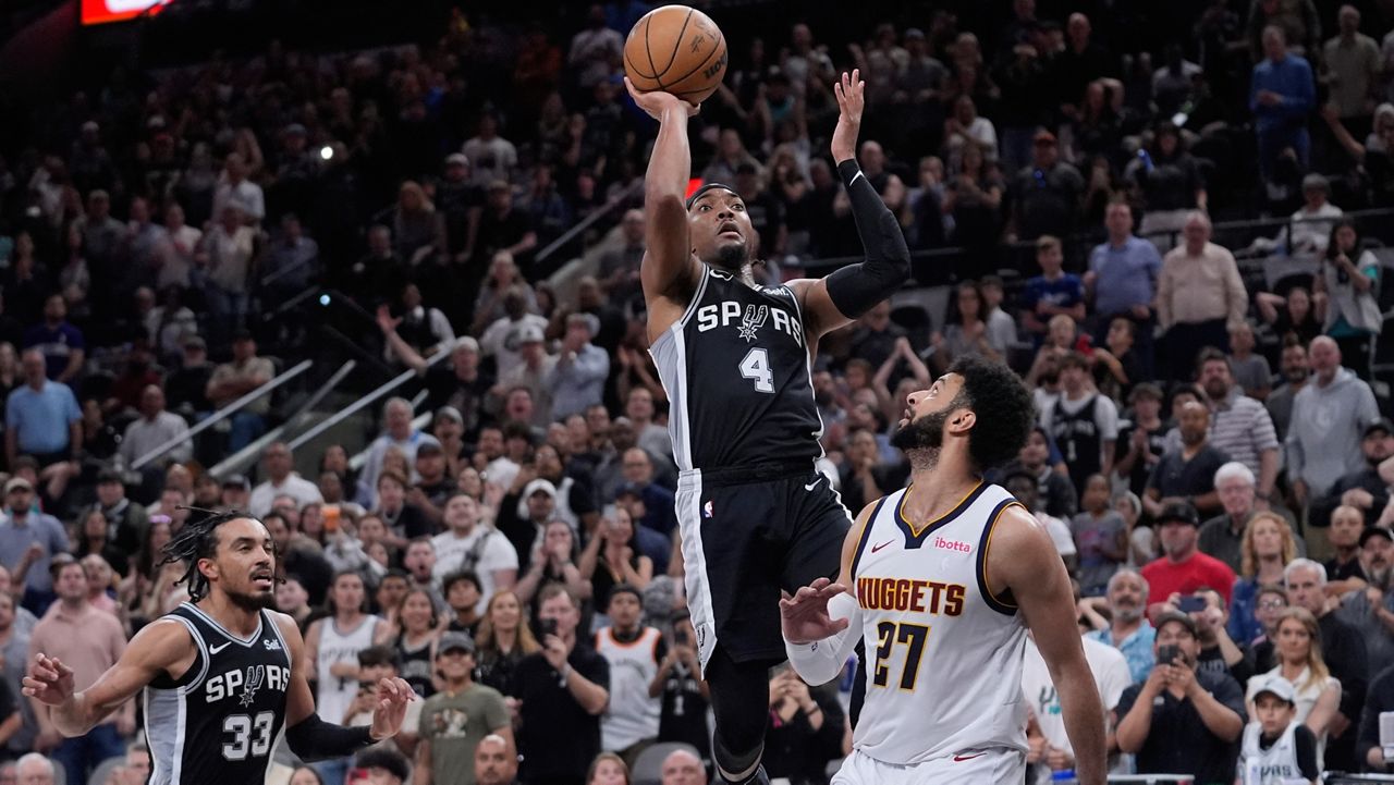 San Antonio Spurs guard Devonte' Graham (4) scores the winning shot over Denver Nuggets guard Jamal Murray (27) during the second half of an NBA basketball game in San Antonio, Friday, April 12, 2024. (AP Photo/Eric Gay)