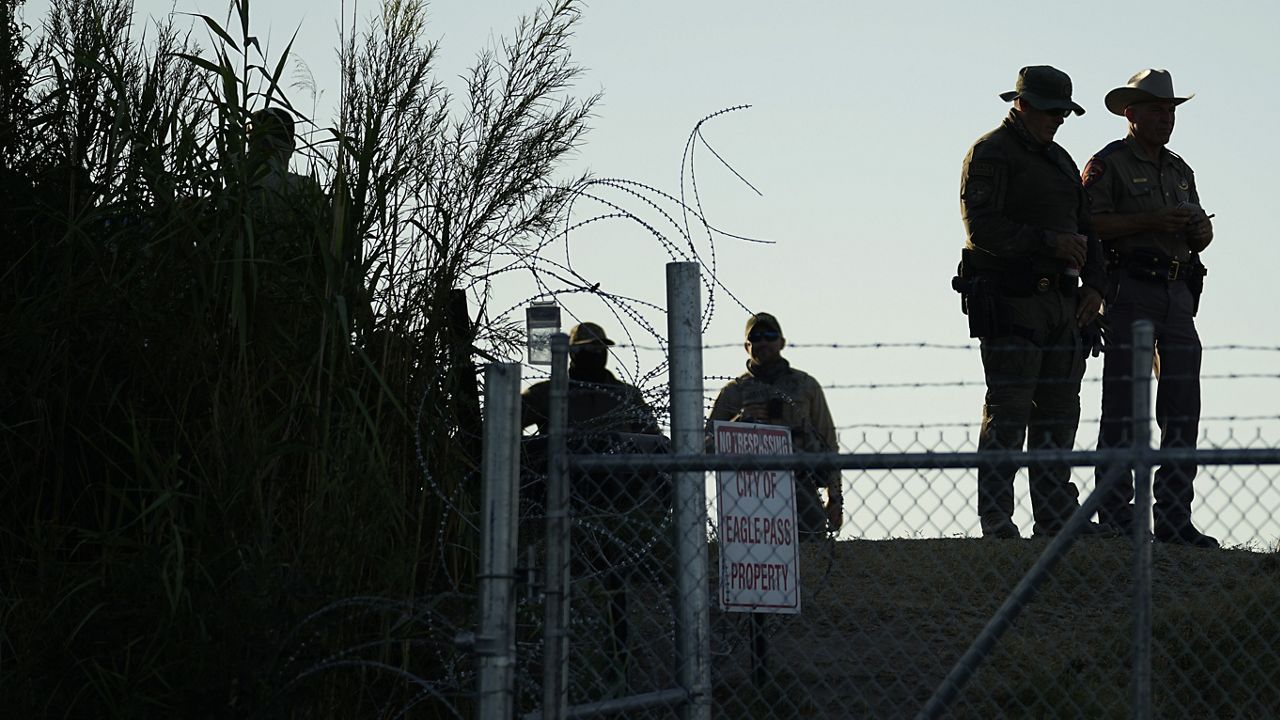 Texas troopers stand near a "No Trespassing" sign and concertina wire along the banks of the Rio Grande at Shelby Park, Aug. 1, 2023, in Eagle Pass, Texas. (AP Photo/Eric Gay)