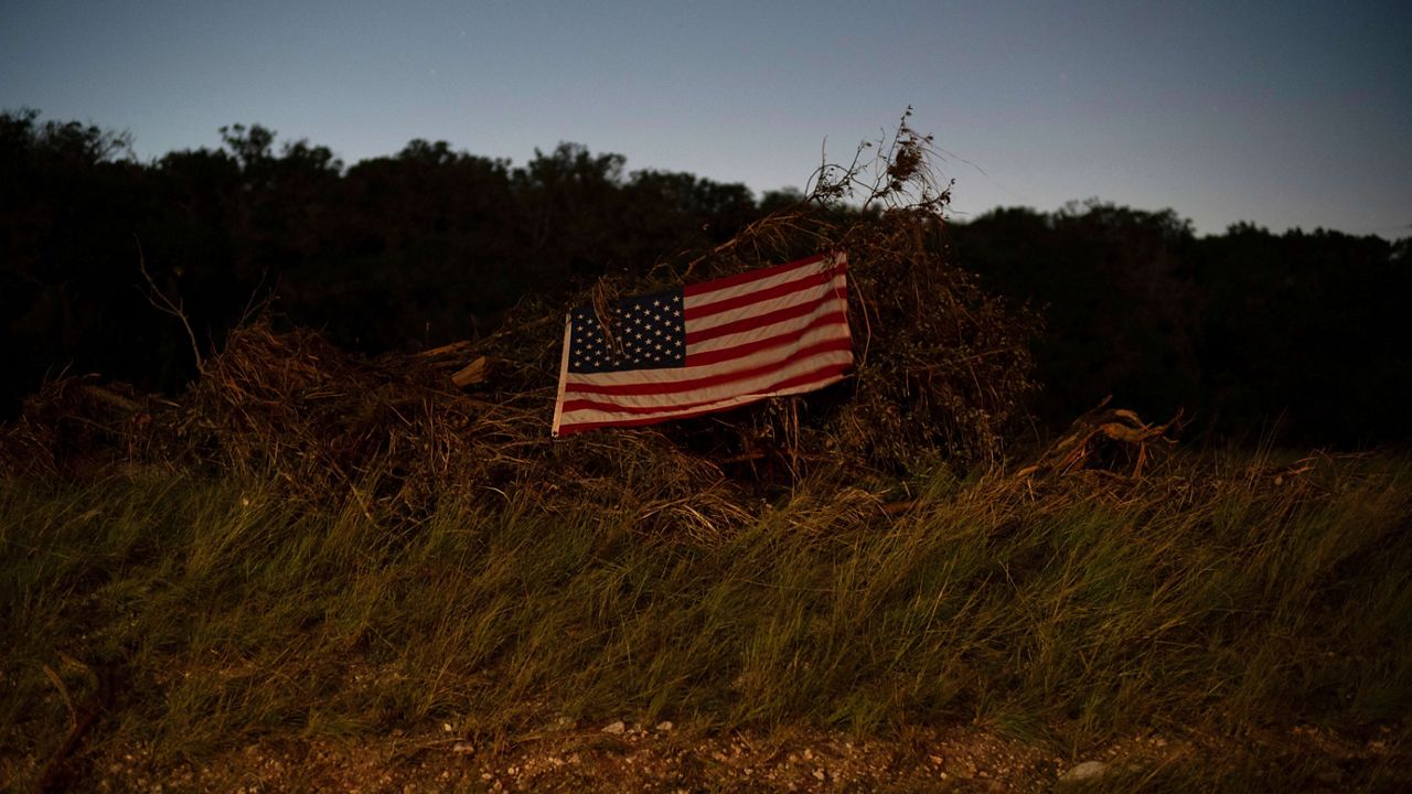 An American flag hangs on debris near Camp Mystic on Tuesday, July 8, 2025, in Hunt, Texas, after a flash flood swept through the area. (AP Photo/Eli Hartman)