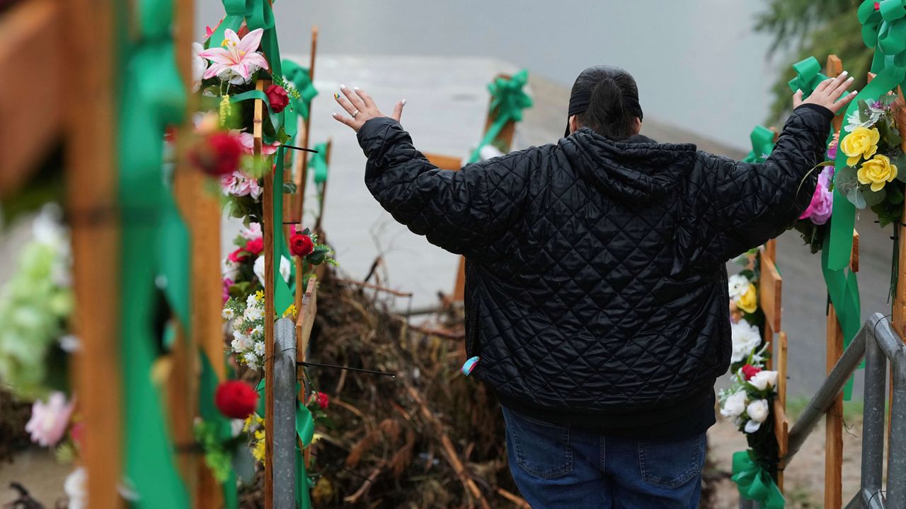 Rain falls as Irene Valdez prays over a makeshift memorial for flood victims along the Guadalupe River, Sunday, July 13, 2025, in Kerrville, Texas. (AP Photo/Eric Gay)