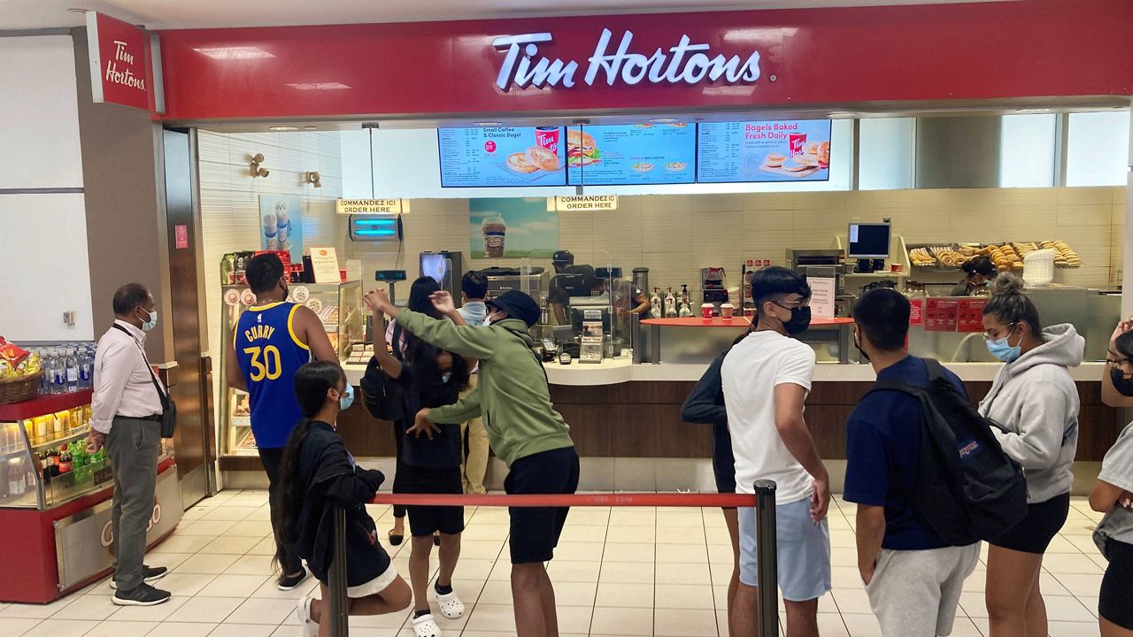 People line up to make purchases at a Tim Hortons fast food restaurant located at Toronto Pearson International Airport in Mississauga, Ontario, Canada, on Friday, July 22, 2022. (AP Photo/Ted Shaffrey)