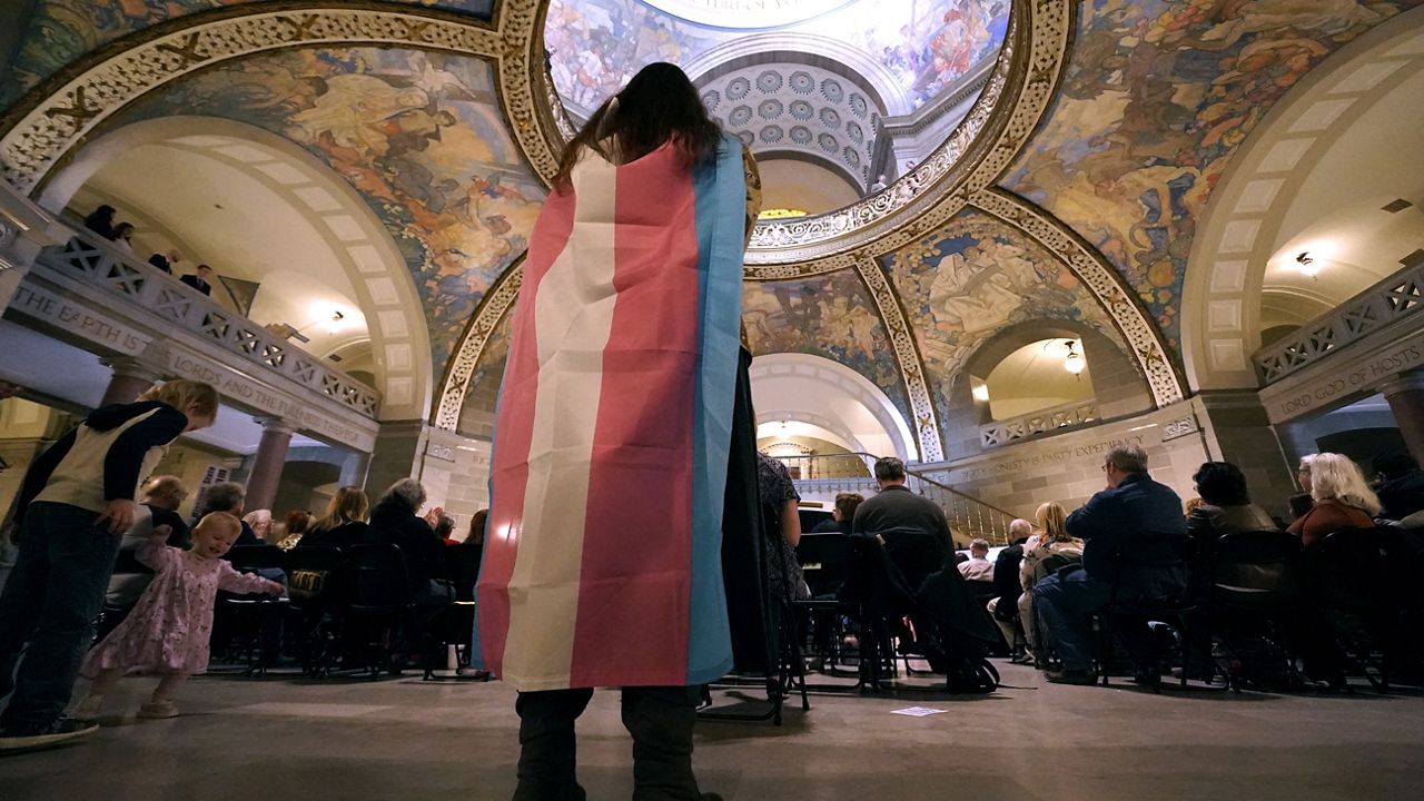 Glenda Starke wears a transgender flag as a counter protest during a rally in favor of a ban on gender-transition health care legislation, March 20, 2023, at the Missouri Statehouse in Jefferson City, Mo. (AP Photo/Charlie Riedel)