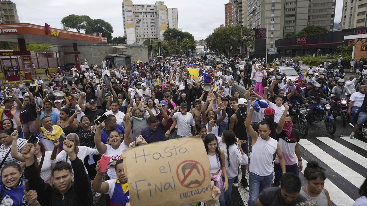 Protesters march against the official election results declaring President Nicolas Maduro the winner, the day after the presidential election in Caracas, Venezuela, Monday, July 29, 2024. The sign reads in Spanish 