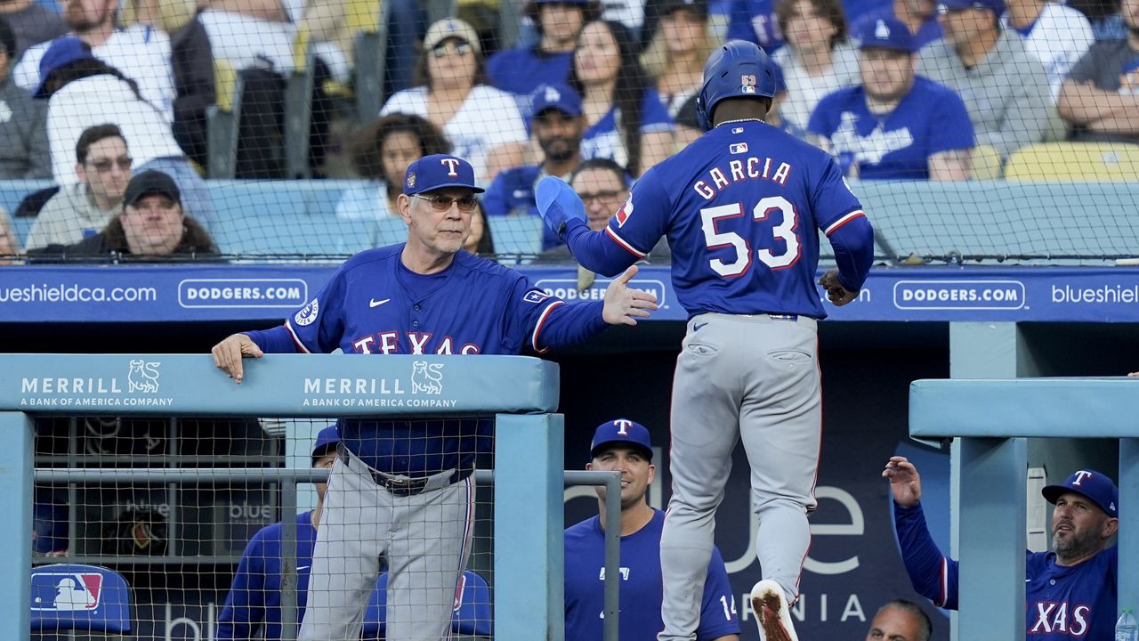 Texas Rangers' Adolis Garcia, right, celebrates with manager Bruce Bochy after scoring off a single hit by Wyatt Langord during the first inning of a baseball game against the Los Angeles Dodgers, Thursday, June 13, 2024, in Los Angeles. (AP Photo/Ryan Sun)