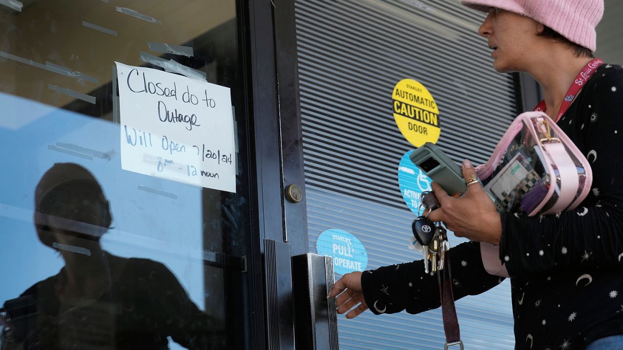 Danielle Tuttle tries the door to a department of motor vehicles location to find it locked and the location closed due to an outage Friday, July 19, 2024, in St. Louis. (AP Photo/Jeff Roberson)