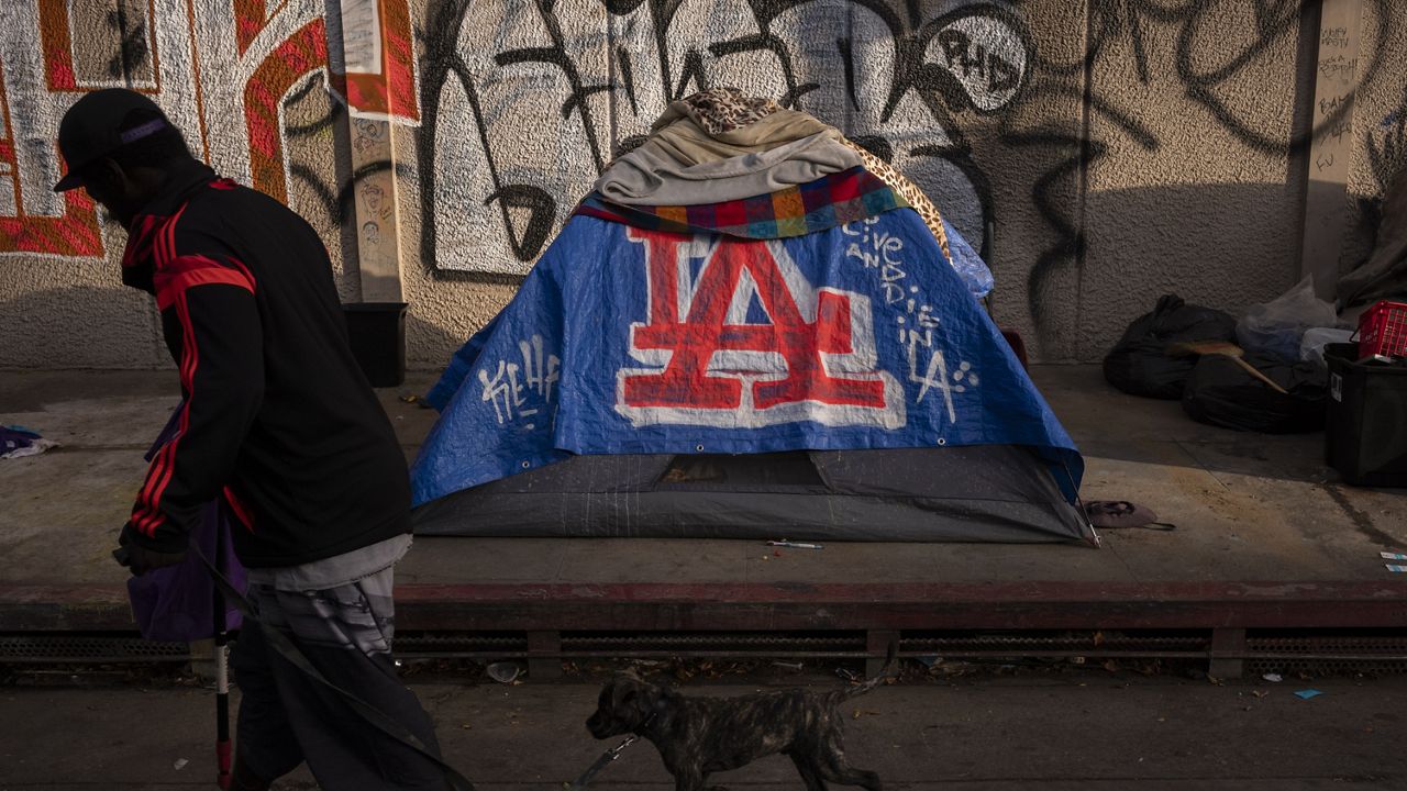 A man walks past a homeless encampment in downtown Los Angeles, Wednesday, Oct. 25, 2023. (AP Photo/Jae C. Hong, File)