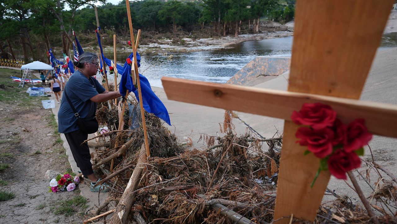Len Arredondo places flowers at a make-shift memorial for flood victims set up along the banks of the Guadalupe River, Saturday, July 12, 2025, in Kerrville, Texas. (AP Photo/Eric Gay)