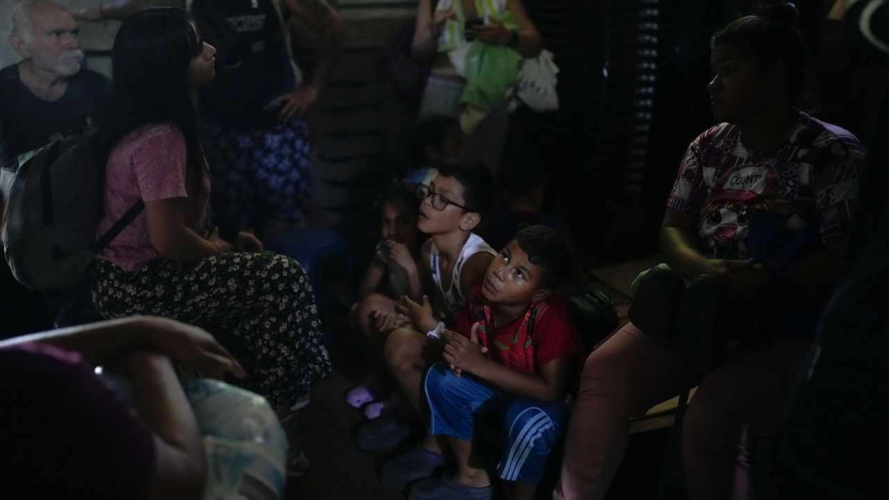 Venezuelan migrant Daniel Dura, second from right, waits next to his mother Rannely Duran inside a house before crossing the Suchiate River, which marks the border between Guatemala and Mexico, from Tecun Uman, Guatemala, Sunday, Oct. 27, 2024. (AP Photo/Matias Delacroix)