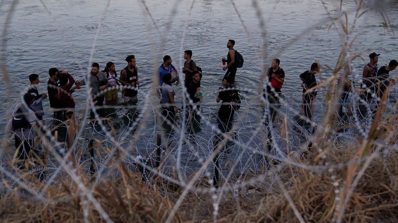 Migrants wait to climb over concertina wire after they crossed the Rio Grande and entered the U.S. from Mexico, Saturday, Sept. 23, 2023, in Eagle Pass, Texas.  (AP Photo/Eric Gay, File)